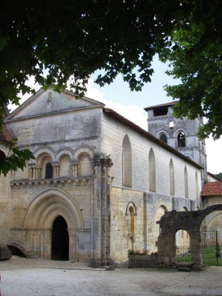 Vue extérieure de l'abbaye de Chancelade en Dordogne sous un ciel clair, mettant en valeur son architecture historique.