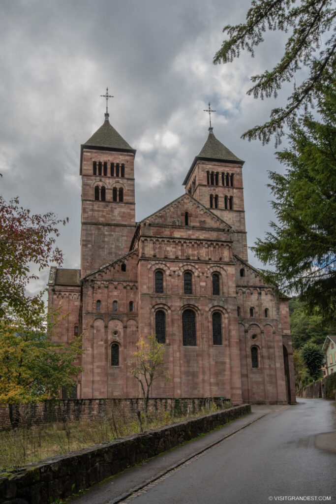 Façade imposante de l'abbaye de Murbach entourée de verdure en Alsace