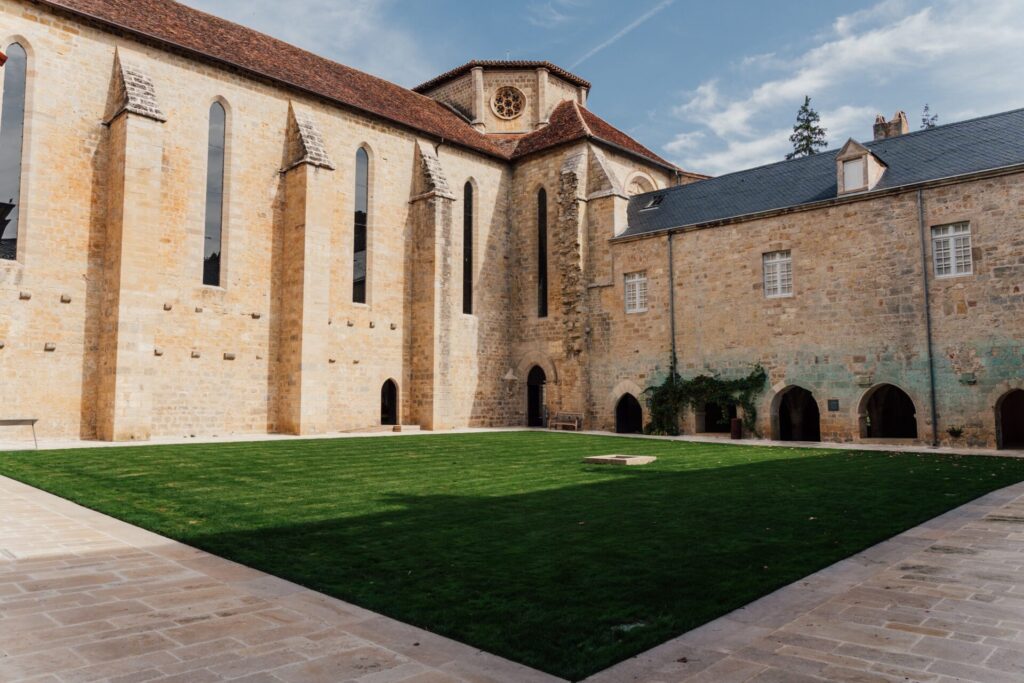 Façade majestueuse de l'abbaye de Beaulieu-en-Rouergue entourée de verdure