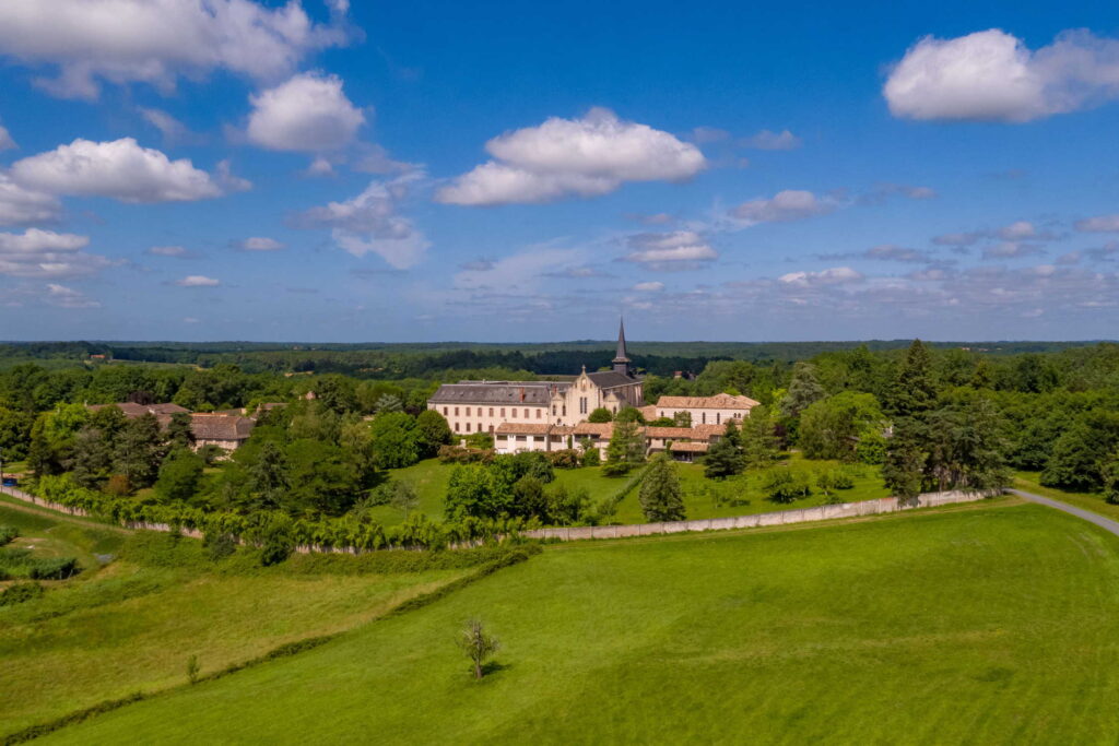Vue aérienne de l'Abbaye d'Échourgnac entourée de verdure en Dordogne