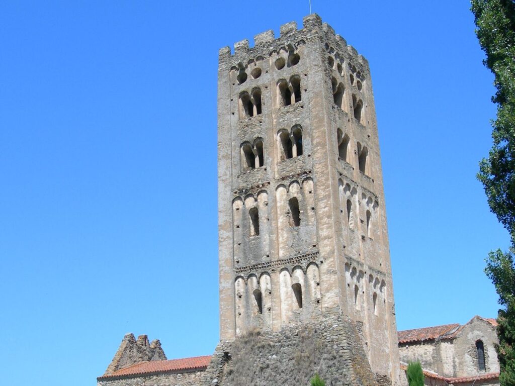 Vue panoramique de l'Abbaye Saint-Michel de Cuxa entourée de verdure, mettant en valeur son architecture historique.