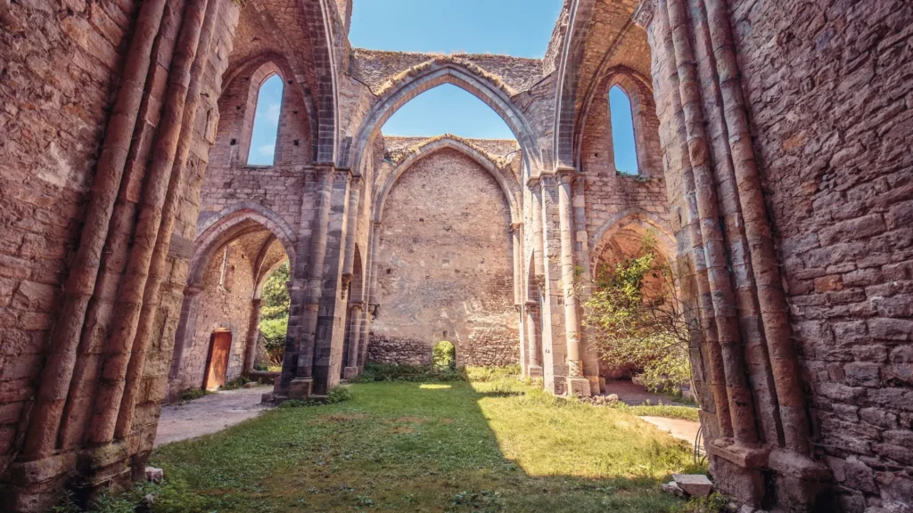 Vue panoramique de l'Abbaye de Villelongue entourée de verdure, mettant en valeur son architecture médiévale.